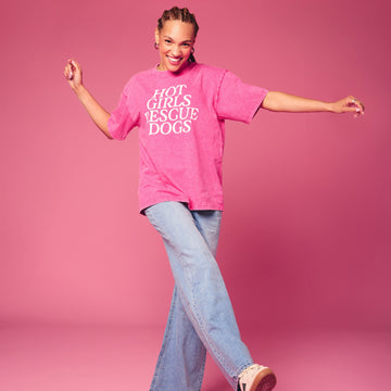 Person wearing a pink oversized t-shirt with text on a pink background