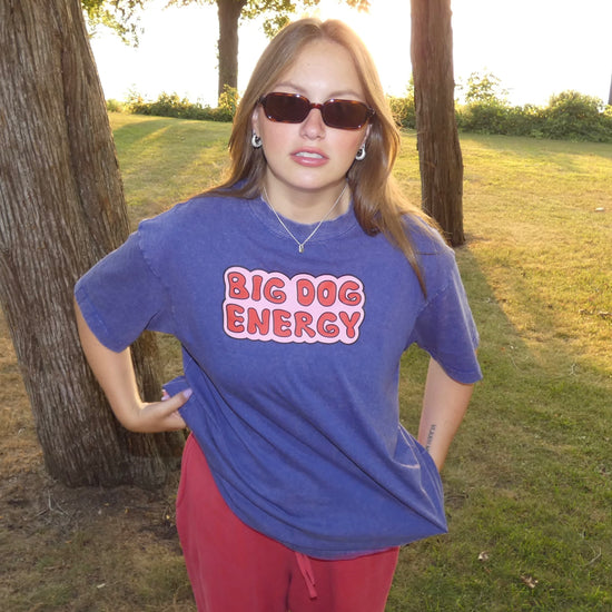 Woman wearing a blue t-shirt with 'BIG DOG ENERGY' text in a park setting