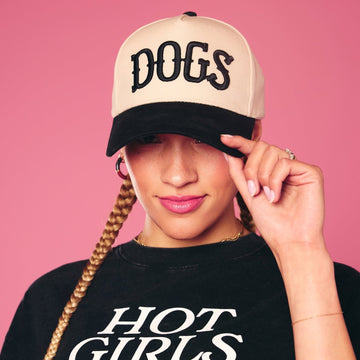 Person wearing a cap with 'DOGS' text and a shirt with 'HOT GIRLS' text on a pink background