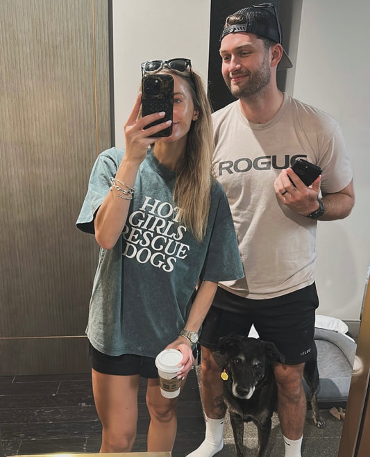Two people taking a mirror selfie with a dog. The girl wears a green tee with the Hot Girl Rescue Dogs text
