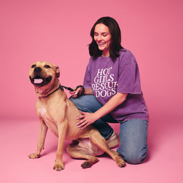 Woman in a purple shirt with a dog on a pink background